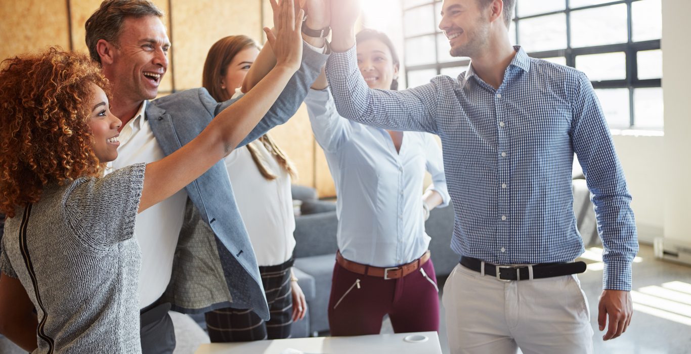 Cropped shot of a group of businesspeople high fiving in the office